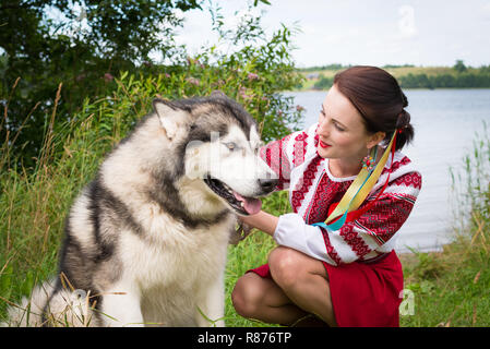 Mädchen Kleider in einem traditionellen slawischen Kleidung petting einen Hund Stockfoto