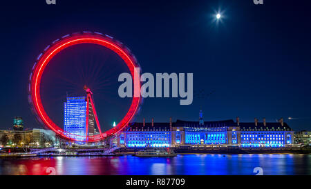 Millennium Wheel, London Eye auf der Southbank London neben dem London Aquarium bei Nacht mit Lichtern, die sich in der Themse spiegeln Stockfoto