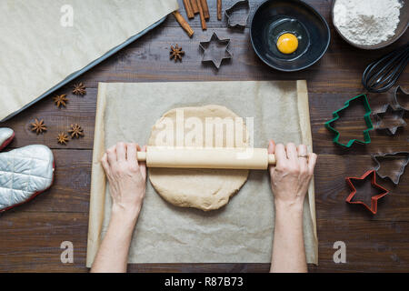 Hausgemachte Weihnachtsplätzchen auf Pergament. Frau rollt Teig. Weihnachten. Der Prozess der backen hausgemachte Cookies. Stockfoto