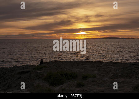 PALMA DE MALLORCA, SPANIEN - 24. NOVEMBER 2018: Silhouette Menschen mit Angeln und Meer mit Horizont bei Sonnenuntergang am 24. November 2018 auf Mallorca, S Stockfoto