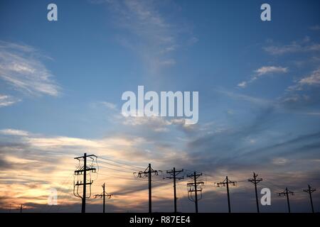 Umspannwerk-Stromverteilung, Versorgungsmasten und Hochspannungsnetzkabel Silhouette bei Sonnenuntergang in Wyoming, USA Stockfoto