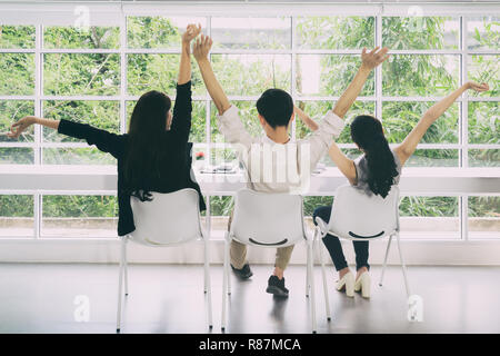 Gruppe von asiatischen Geschäft Leute recken die Arme in die Luft, während der Arbeit mit Tablet in seinem Büro. Stockfoto