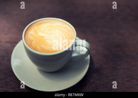 Heiße kunst Latte Kaffee in einer Tasse auf hölzernen Tisch in Coffee Shop. Stockfoto