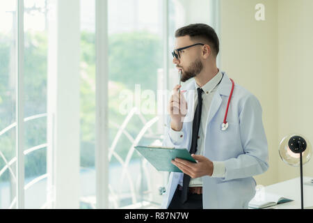 Porträt der jungen kaukasischen männlicher Arzt posiert mit verschränkten Armen und schauen durch das Fenster kopieren. Denken. Stockfoto