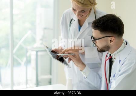 Zwei Doktoren der Analyse und Beratung über medizinische Aufzeichnung im modernen Krankenhaus. Kaukasische Ärzte reden über Bericht. Stockfoto