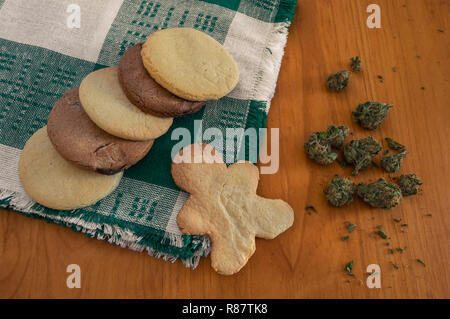 Cannabis essbar: Cookies mit Marihuana. Cookies mit THC. Hausgemachte Cookies auf ein Tuch, Serviette und ein Haufen von Marihuana Knospen auf Holztisch. Stockfoto