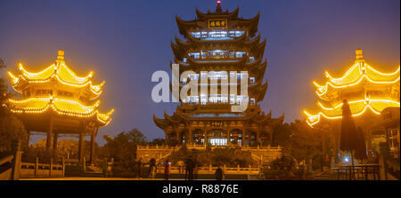 Horizontale nächtliche Foto von Yellow Crane Tower in Wuhan, China, während der blauen Stunde. Turm hat blaue Lichter leuchten und zwei Pavillons beleuchtet orange Stockfoto