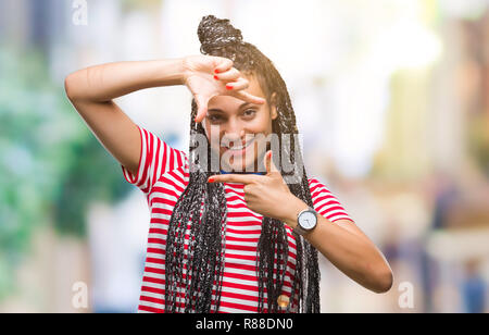 Junge geflochtenes Haar African American Girl über isolierte Hintergrund lächelnd, Rahmen mit Händen und Fingern, glückliches Gesicht. Kreativität und Photogra Stockfoto