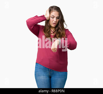 Schöne Übergrößen junge Frau über isolierte Hintergrund ein Blick auf die Uhr Zeit Sorgen, Angst, sich spät Stockfoto