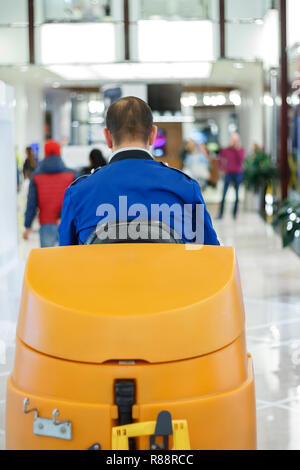 Reiniger in blauer Uniform auf eine Kehrmaschine in einem Einkaufszentrum Stockfoto