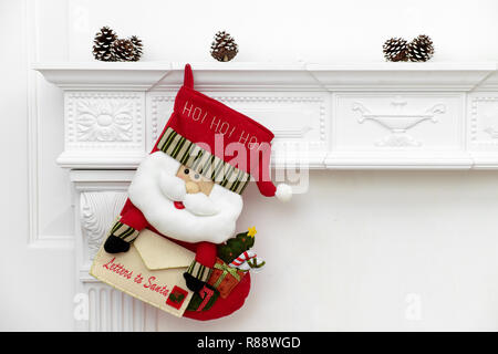 Ein Bild schließen der schön dekorierten Santa Weihnachten Socken mit Ho! Ho! Ho! Wort hängen an einem Kamin warten auf präsentiert. Stockfoto