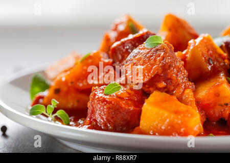 Eintopf aus Schweinefleisch gebratene Würstchen mit Kartoffeln und Tomaten Sauce, Ansicht schließen Stockfoto