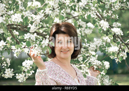 Portrait von Frau über ein blühender Apfelbaum im Frühjahr Stockfoto