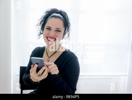 Porträt einer wunderschönen normale Frau mit ihrem Mobiltelefon und lächelnd mit schwarzem Haar, weiße Haut und rote Lippen. Platz kopieren Stockfoto