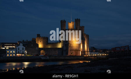 Caernarfon Castle, oft als anglicized Carnarvon Castle, ist eine mittelalterliche Festung in Caernarfon, Gwynedd, Nord-West Wales. Hier ist abends beleuchtet Stockfoto