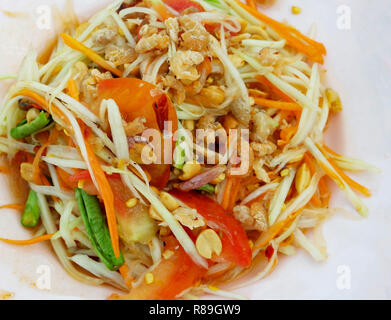 Das Essen im Thai Stil Papaya Salat/close up Papaya Salat auf Teller heiß und würzig mit Erdnuss getrocknete Garnelen Yard lange Bohnen und Tomaten Stockfoto