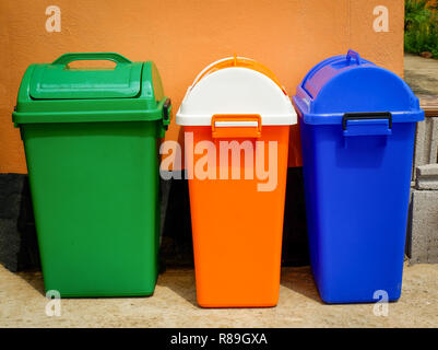 Bunte bin draußen/Nahaufnahme von papierkörben Ständer an der Wand grün Orange und Blau bin verschiedene Größen im Garten Park Stockfoto