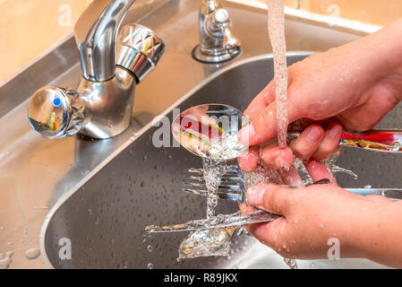 Besteck waschen unter fließendem Wasser in der Küche, Hände, Nahaufnahme Stockfoto