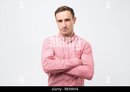 Traurig, unglücklich, junger Mann im rosa Hemd hat mürrischen Ausdruck, nachdem mit Frau streiten. Stockfoto