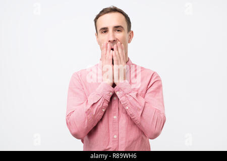 Junger Mann mit seinen Mund mit schockiert mit Gerüchten überrascht oder Stockfoto