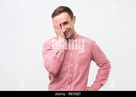 Mann im rosa Hemd an Kamera suchen mit temperamentvoll lustig Ausdruck, seinen Mund zu schließen. Stockfoto