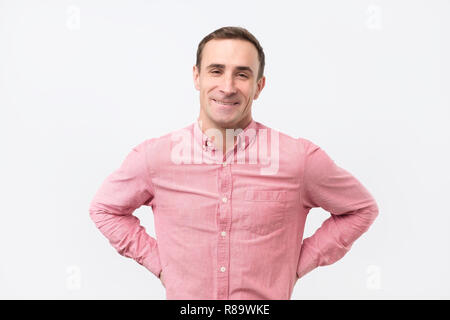 Schönen italienischen Mann mit rosa T-Shirt mit leichten Lächeln posiert vor weißem Hintergrund Stockfoto