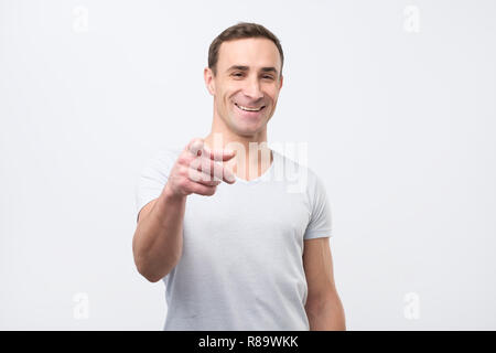 Ich wählen Sie. Glückliche junge Mann, der auf der Kamera und lächelnd Stockfoto