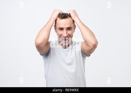 Junger Mann, der nicht in seinem eigenen Glück glauben kann, erregt werden, halten sich an den Händen auf Haar Stockfoto