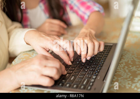 Nahaufnahmen von Frauen Hände Schreiben auf dem Computer. Tochter zeigt Ihre Mutter wie auf einem Laptop zu drucken. Hände über Computer ein. Stockfoto