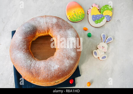 Reindling - deutsche oder österreichische Festliche yeasty Backen für Ostern. Ring Kuchen serviert auf einer Holzplatte auf einen weissen Stein Hintergrund. Stockfoto