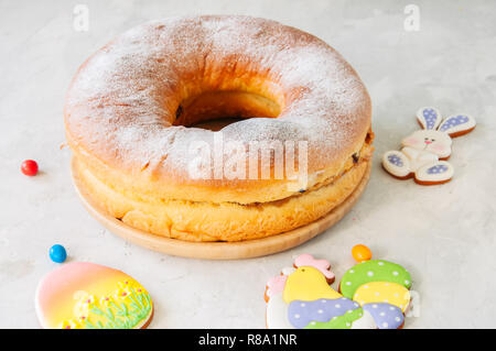 Reindling - deutsche oder österreichische Festliche yeasty Backen für Ostern. Ring Kuchen serviert auf einer Holzplatte auf einen weissen Stein Hintergrund. Stockfoto