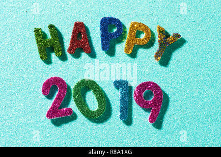 Nahaufnahme von einigen glitter Buchstaben und Zahlen in verschiedenen Farben, die den Text gerne 2019, auf einem blauen Glitzer Hintergrund Stockfoto