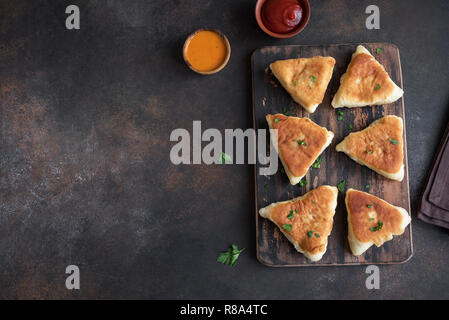 Frittierte Gemüse Kuchen mit Soßen, samsa, Samosas, echpochmak - traditionelle Fleisch oder vegetarisch gefüllte Pasteten Pasteten auf rustikalen Hintergrund, kopieren. Stockfoto