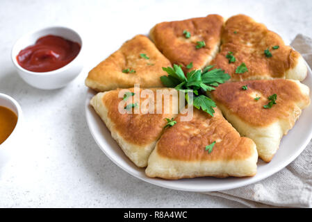 Frittierte Gemüse Kuchen mit Soßen, samsa, Samosas, echpochmak - traditionelle Fleisch oder vegetarisch gefüllte Pasteten Pasteten auf weißem Hintergrund, aus der Nähe. Stockfoto