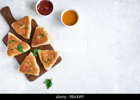 Frittierte Fleischpasteten mit Soßen, samsa, Samosas, echpochmak - traditionelle Fleisch oder vegetarisch gefüllte Pasteten Pasteten auf weißem Hintergrund, kopieren. Stockfoto