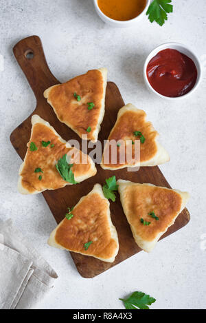 Frittierte Fleischpasteten mit Soßen, samsa, Samosas, echpochmak - traditionelle Fleisch oder vegetarisch gefüllte Pasteten Pasteten auf weißem Hintergrund, kopieren. Stockfoto