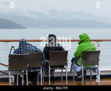 Kreuzfahrtschiff Passagiere in warme Kleidung sitzen Sie auf Deck genießen die malerische Küste Alaskas an einem kalten Tag. Stockfoto