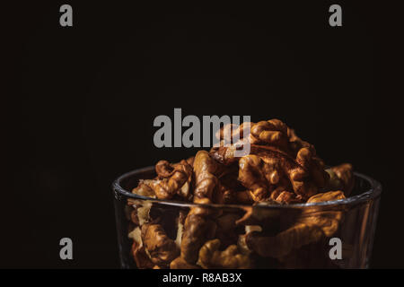 Nahaufnahme Blick auf ohne Schale Walnüsse in Glas auf schwarzem Hintergrund Stockfoto