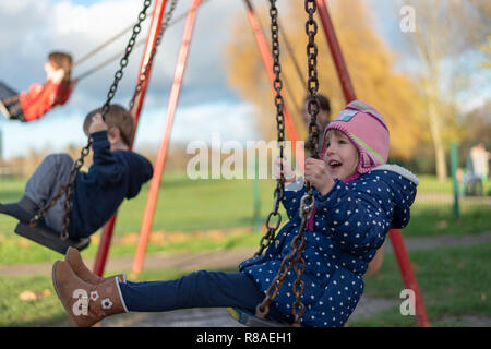 Pre-school im Alter von kaukasischen Frauen auf dem Spielplatz auf der Schaukel Stockfoto