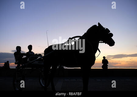 Silhouetted Fußgänger wandern in Roxas Boulevard zu einem beliebten Uferpromenade, die sich entlang der Küste der Bucht von Manila in der Stadt Manila, die Hauptstadt der Philippinen. Stockfoto