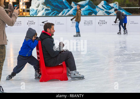 Bournemouth, Dorset, Großbritannien. 14. Dezember 2018. Besucher viel Spaß beim Eislaufen auf dem freien temporäre Eislaufbahn in Bournemouth Garten an einem Bitterkalten bewölkten Tag. Junge Mann in den Sitz drückt auf dem Eis - rollentausch! . Credit: Carolyn Jenkins/Alamy leben Nachrichten Stockfoto