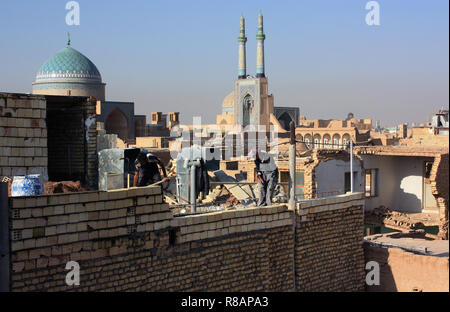 Yazd, Iran. 24 Okt, 2018. Iran - Yazd, auch Jasd, ist eine der ältesten Städte des Iran und Hauptstadt der gleichnamigen Provinz. Blick über die Dächer, Bau Arbeiter auf dem Dach eines alten Stadthaus. Im Hintergrund Teile der Moschee Amir Chakhm‰ gh (Amir-Chakmak) und die seyed Rokn Addin Mausoleum. Am 24.10. 2018. Credit: Rolf Zimmermann | Verwendung weltweit/dpa/Alamy leben Nachrichten Stockfoto