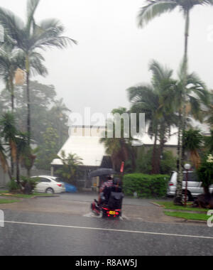 Cairns, Australien, 15. Dez 2018. Erste Stürme aus tropischen Zyklon Owen haben lokalisierte Überschwemmung in Far North Queensland verursacht. Mann auf Mobilität scooter fährt durch Hochwasser im Vorort Edge Hill, Cairns, Queensland, Australien. Credit: Suzanne Long/Alamy leben Nachrichten Stockfoto