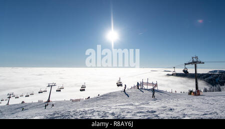 Feldberg im Schwarzwald, Deutschland. 15 Dez, 2018. Skifahrer Fahrt unter einem Sessellift über dem Meer der Wolken. Die ersten Aufzüge auf dem Feldberg im Schwarzwald eröffnet. Quelle: Patrick Seeger/dpa/Alamy leben Nachrichten Stockfoto