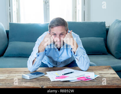 Besorgt und verzweifelten Unternehmer junger Mann Berechnung Rechnungen Steuern und Finanzen zählen Unternehmen oder zu Hause auf der Couch zu Hause sitzen in Zahlen Stockfoto