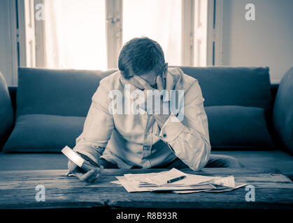 Besorgt und verzweifelten Unternehmer junger Mann Berechnung Rechnungen Steuern und Finanzen zählen Unternehmen oder zu Hause auf der Couch zu Hause sitzen in Zahlen Stockfoto