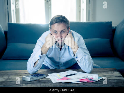 Besorgt und verzweifelten Unternehmer junger Mann Berechnung Rechnungen Steuern und Finanzen zählen Unternehmen oder zu Hause auf der Couch zu Hause sitzen in Zahlen Stockfoto