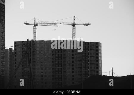 Blick auf die Baustelle mit Kränen und Wohnhochhäuser. Schwarz-weiß Foto. Stockfoto