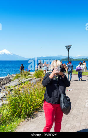 PUERTO VAGAS, CHILE - Januar 10, 2018: Eine Frau mit Kamera auf dem Hintergrund einer Berglandschaft. Kopieren Sie Platz für Text. Vertikale Stockfoto