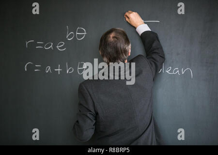 Männliche Oberlehrer Mathematikunterricht, an die Tafel schreiben Stockfoto